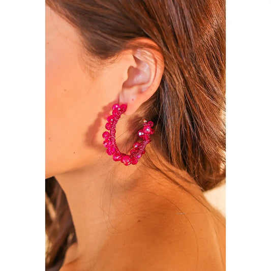 Close-up of a woman wearing the Berry Bling Hoops — bold hot pink beaded hoop earrings with sparkling accents, styled with loose brown hair.