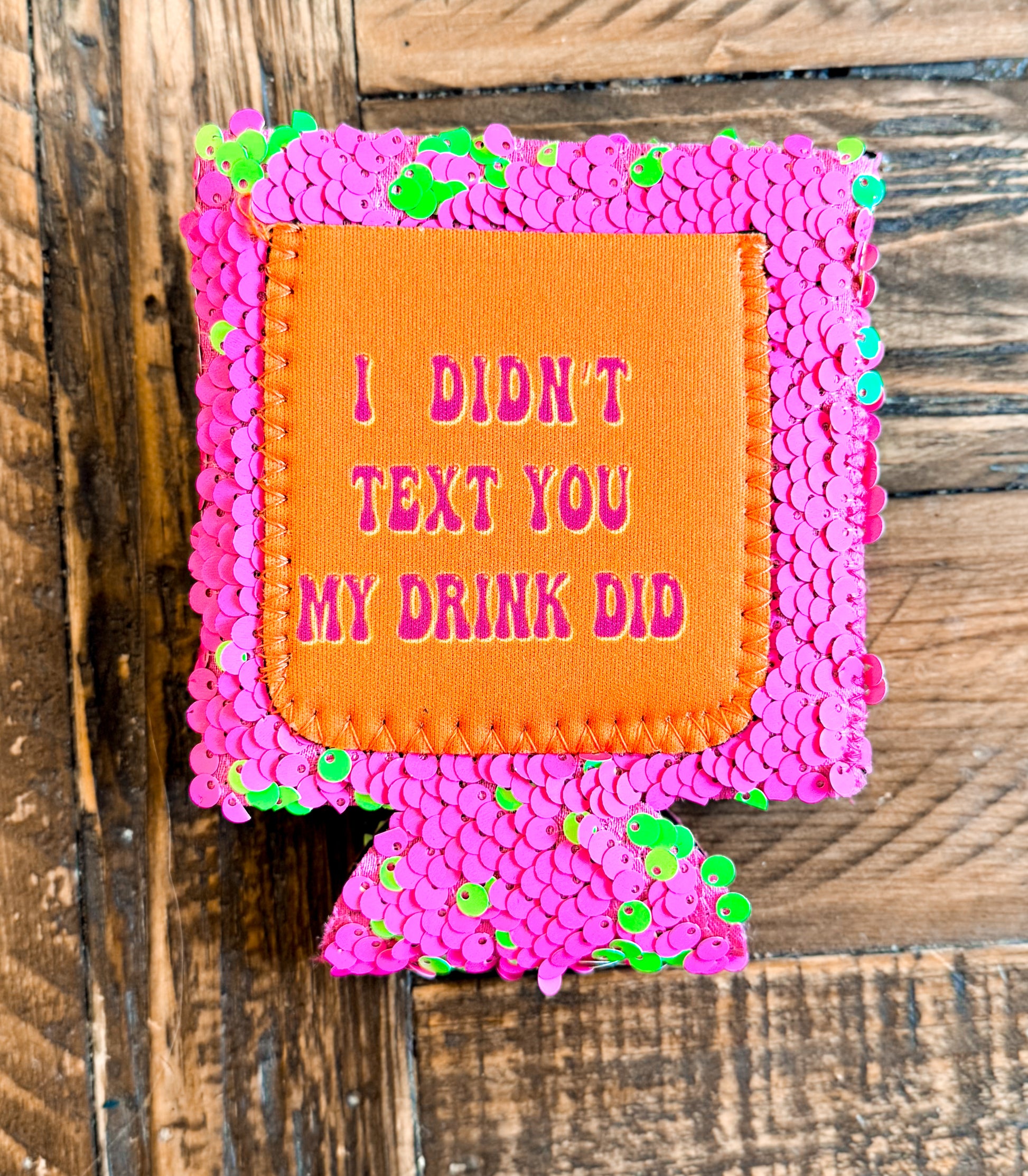 Bright pink sequin can cooler with a neon orange patch that reads âI DIDNâT TEXT YOU, MY DRINK DIDâ in pink lettering.