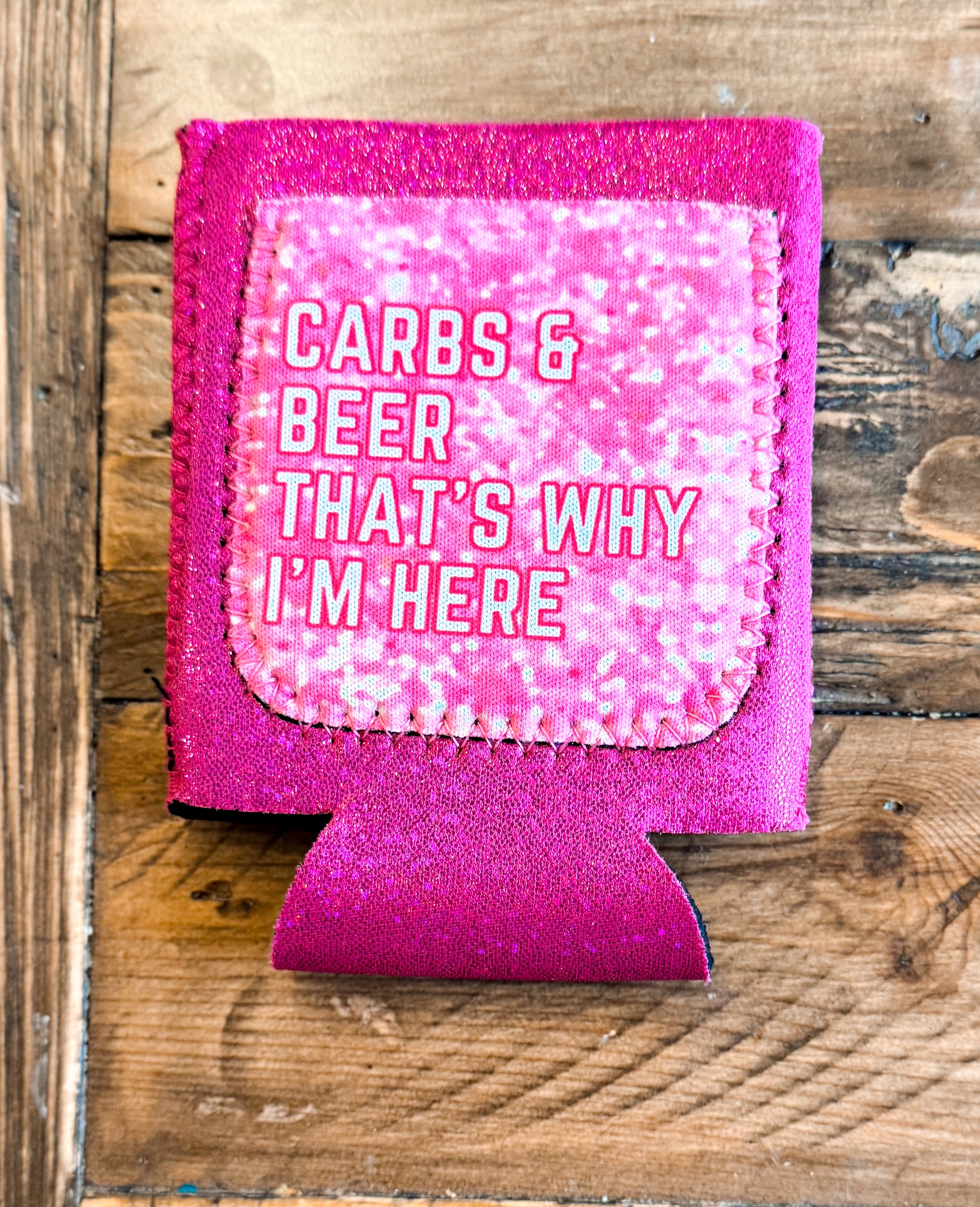 Hot pink glitter can cooler with a light pink patch that says âCARBS & BEER THATâS WHY IâM HEREâ in white outlined text.