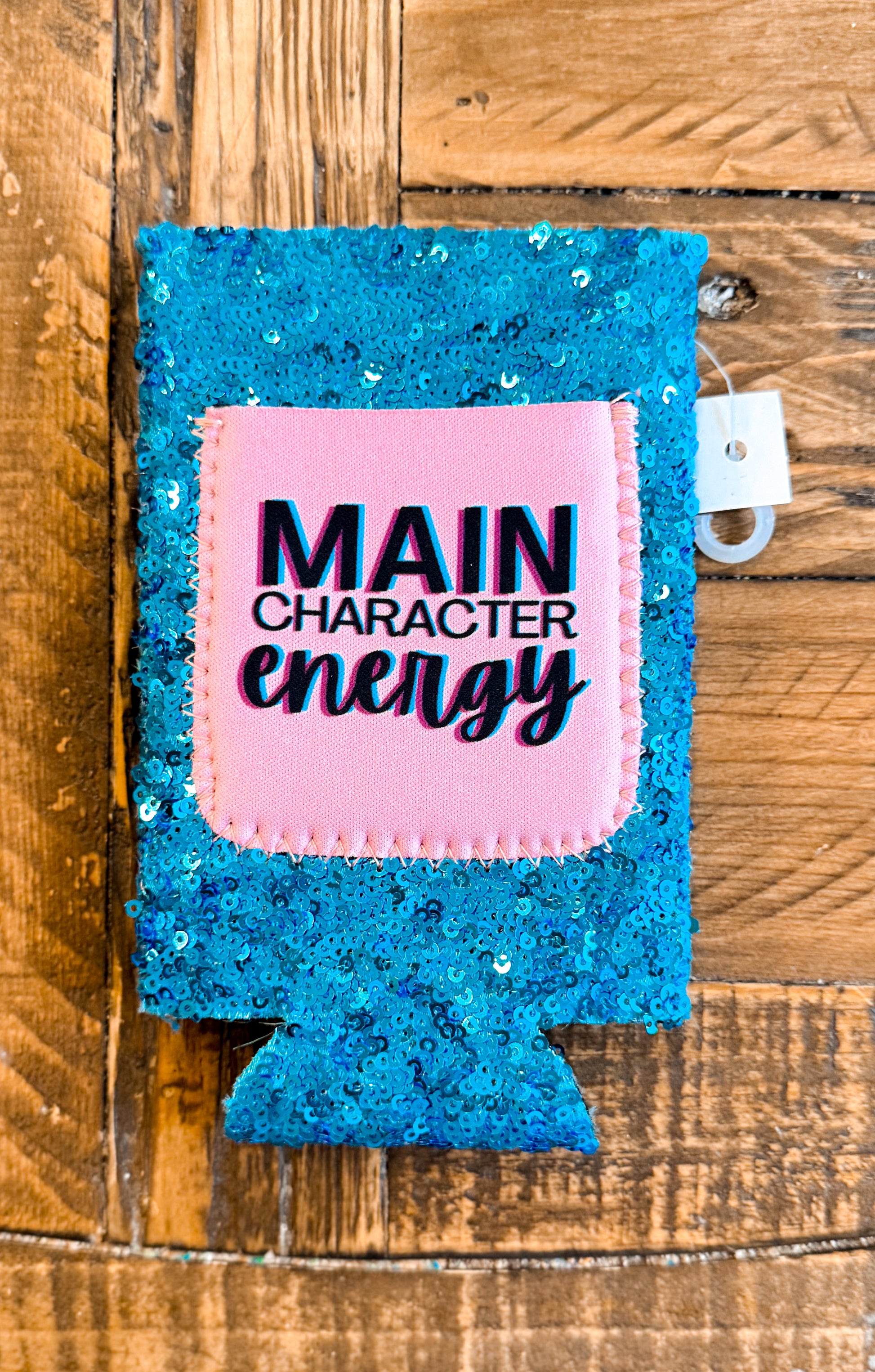 Bright teal sequin slim can cooler with a pink patch that says “MAIN CHARACTER ENERGY” in bold black and pink text with playful font styling.
