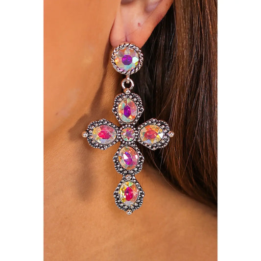 Close-up of the Glitz & Grace Cross Drops — large antique silver cross earrings adorned with iridescent gemstones — worn by a woman with long brunette hair.