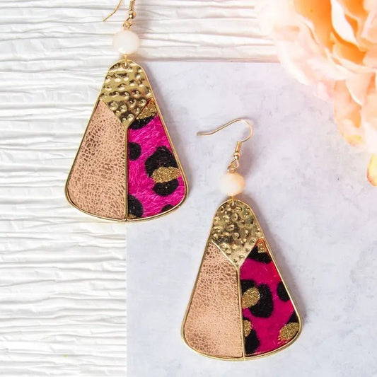 Pair of fan-shaped earrings featuring three sections: hammered gold metal, matte blush leather, and vibrant pink leopard print. Topped with a frosted white bead and gold hook, styled flat against a light background with a peach flower nearby.
