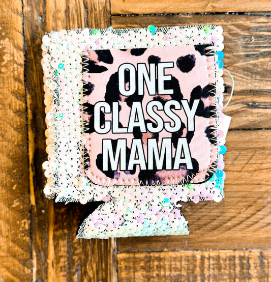 Sequin can cooler with iridescent white sequins and a leopard print patch that reads “ONE CLASSY MAMA” in bold white lettering.