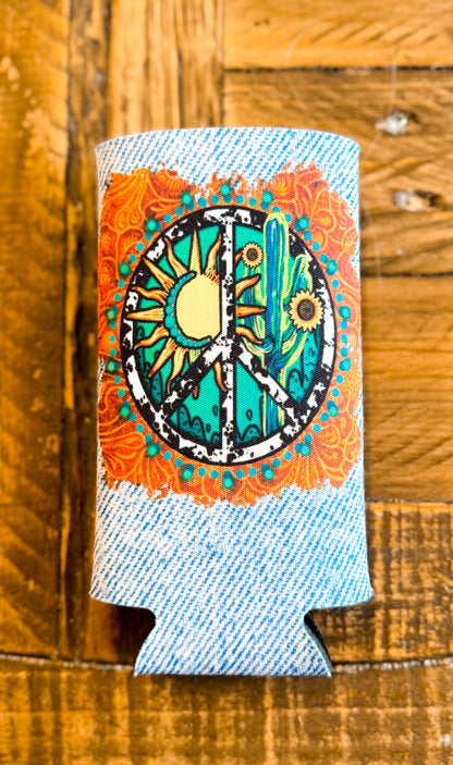 Slim can cooler with a denim-printed background and a vibrant peace sign design featuring a sun, cactus, and sunflowers surrounded by orange and turquoise mandala details.