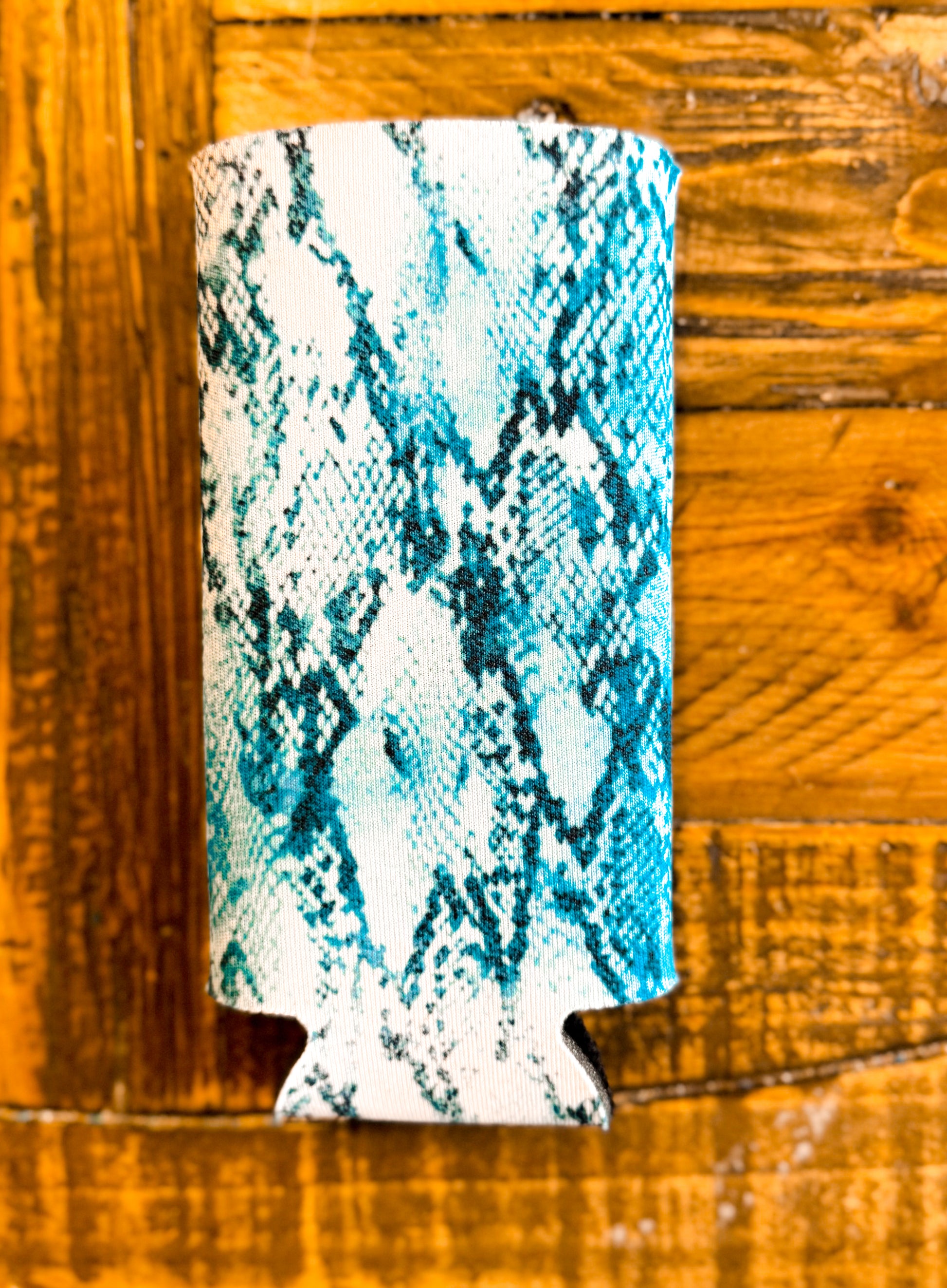 Slim can cooler with a bold teal and white snakeskin print, offering a wild, stylish vibe perfect for girls' night or summer sipping.