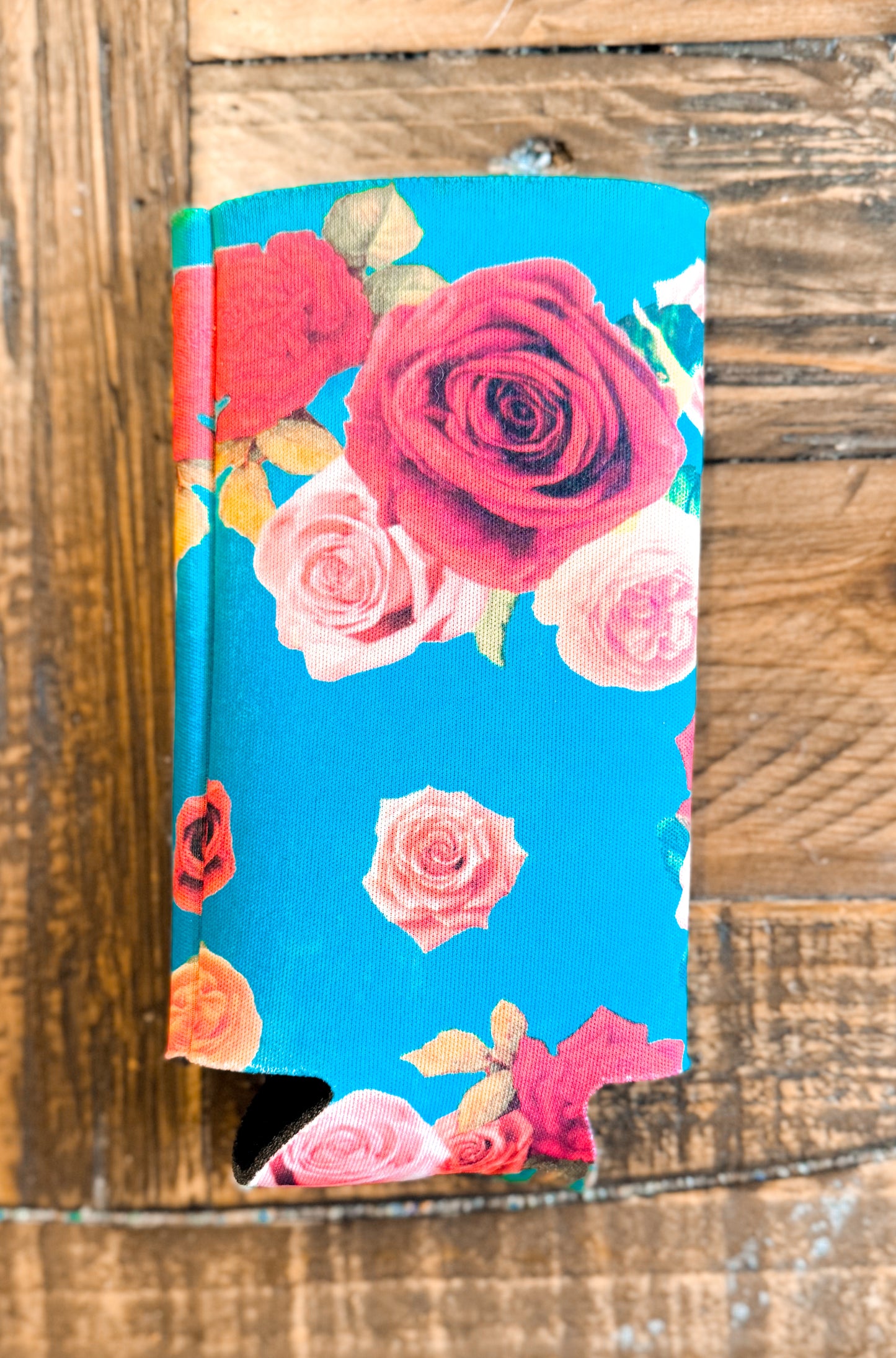 Slim can cooler with a bright turquoise background and a border of assorted roses in red, pink, and peach tones — feminine and fresh.
