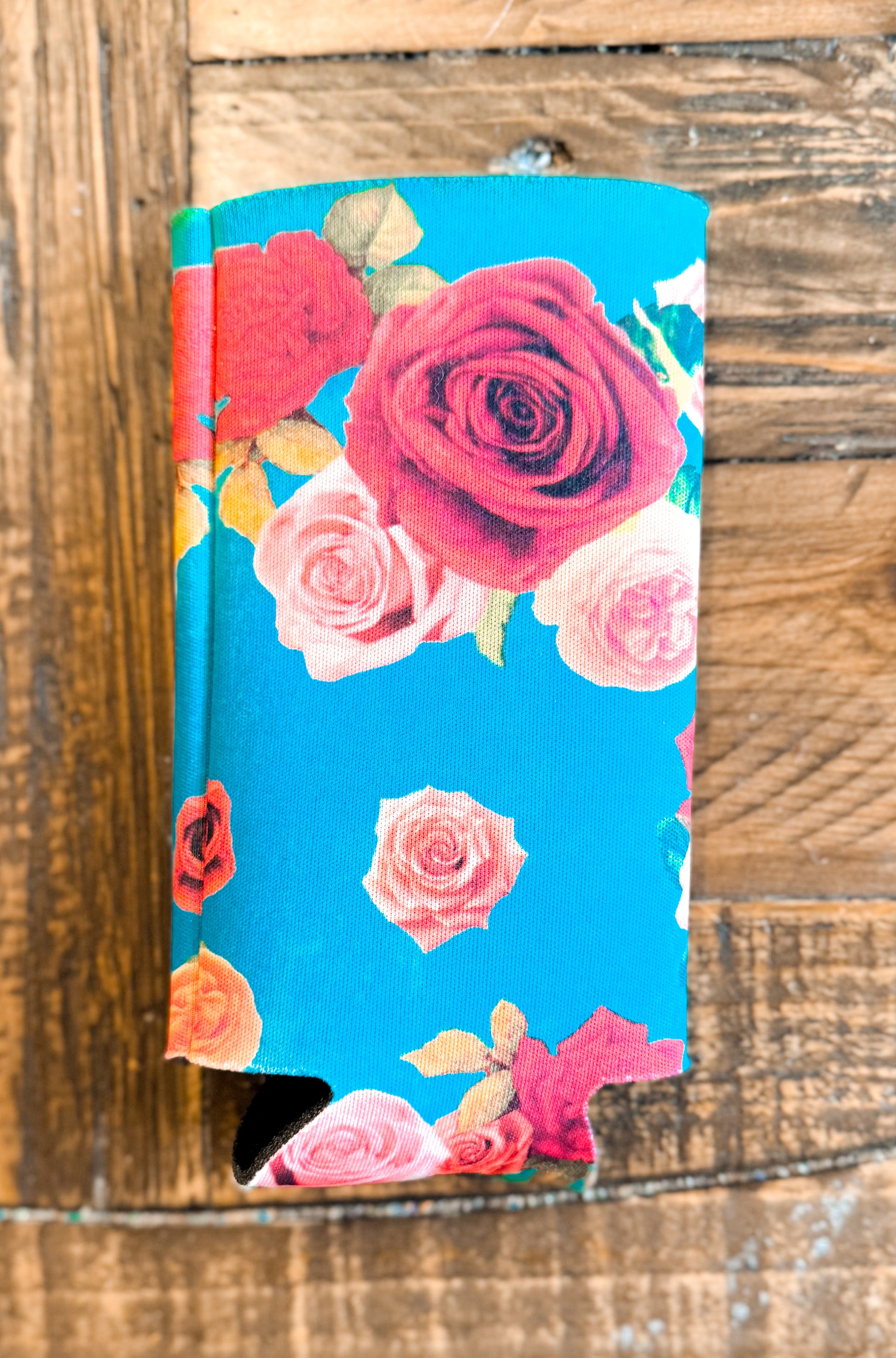 Slim can cooler with a bright turquoise background and a border of assorted roses in red, pink, and peach tones — feminine and fresh.