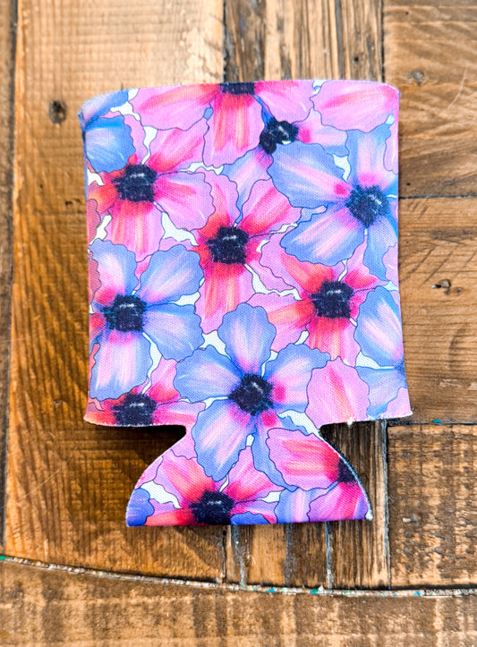 Colorful floral can cooler featuring a bold pattern of red, purple, and blue watercolor-style flowers with dark centers, set against a rustic wood background.